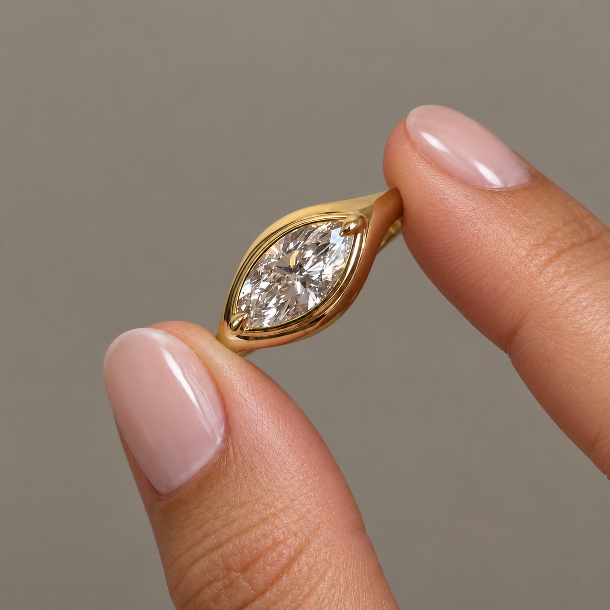 1 ct east-west marquise-cut moissanite bezel-prong ring in 18k yellow gold vermeil, held between two fingertips