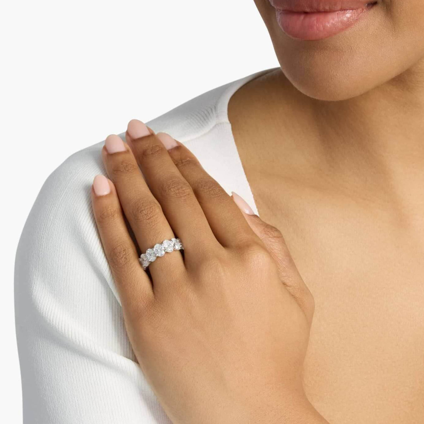 2.5 ct oval-cut moissanite half eternity ring worn on a finger.