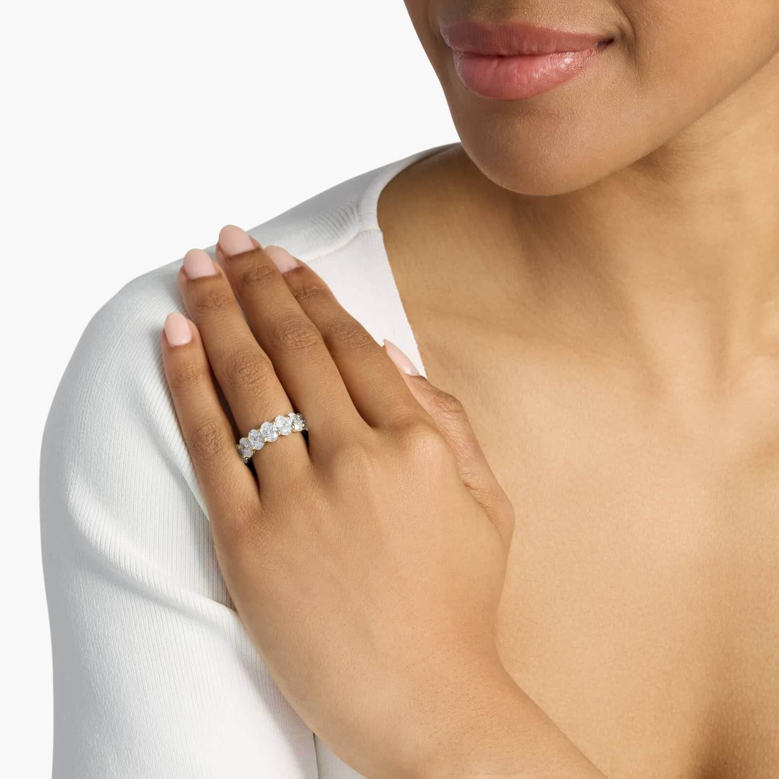 2.5 ct oval-cut moissanite half eternity ring worn on a finger.