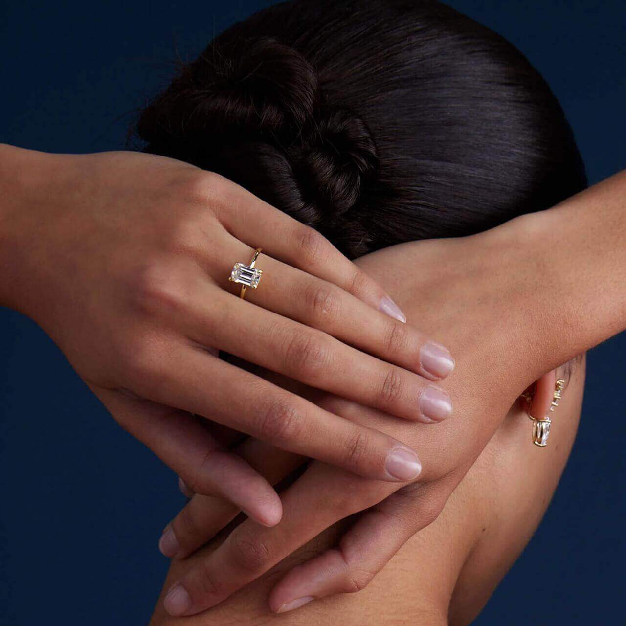 2 ct emerald-cut moissanite solitaire ring worn on a finger.