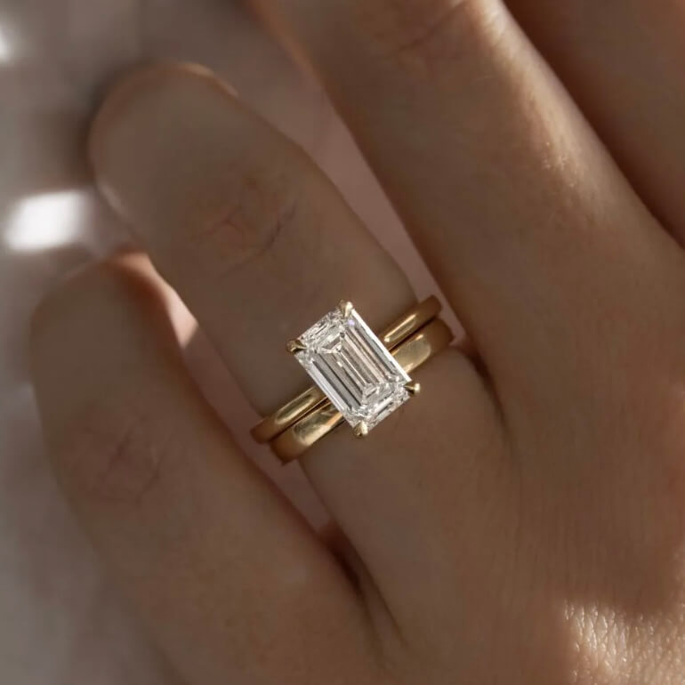2 ct emerald-cut moissanite solitaire ring worn on a finger.