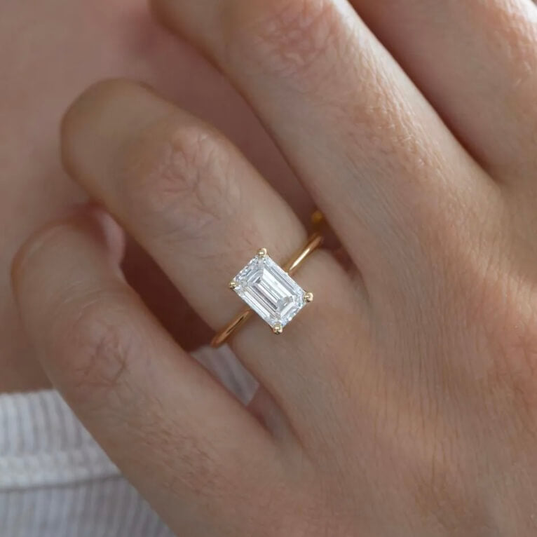 2 ct emerald-cut moissanite solitaire ring worn on a finger.