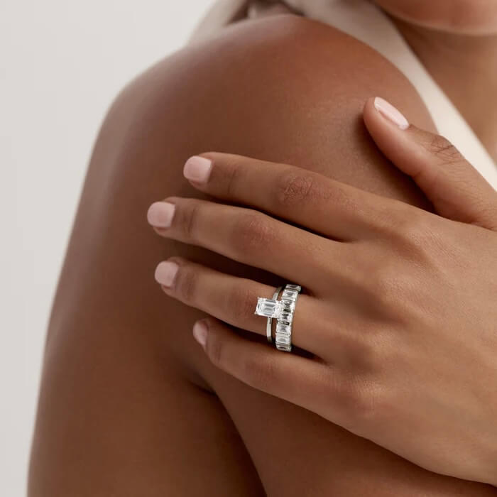 2 ct emerald-cut moissanite solitaire ring worn on a finger.