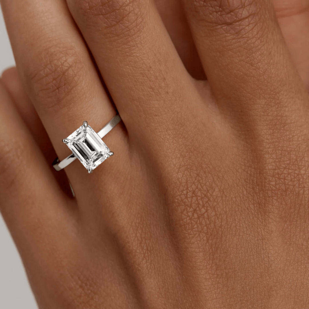 2 ct emerald-cut moissanite solitaire ring worn on a finger.