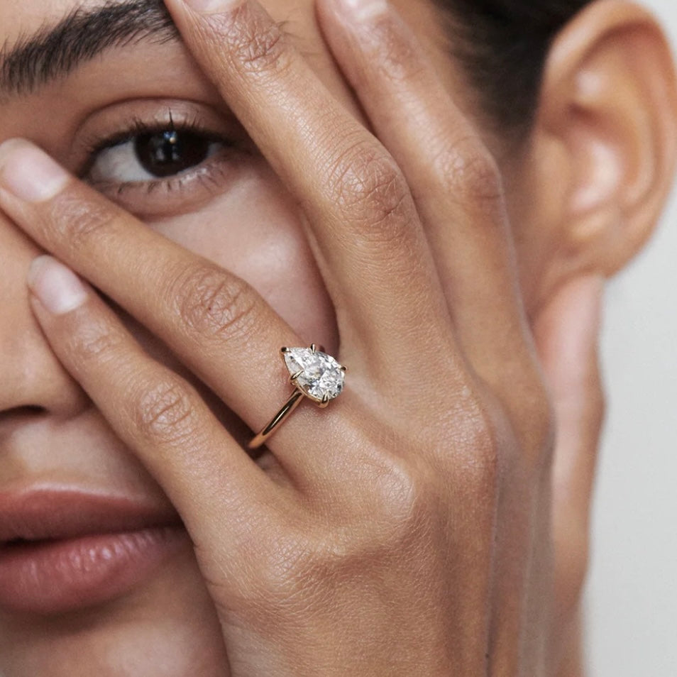 2 ct pear-cut moissanite solitaire ring worn on a finger.