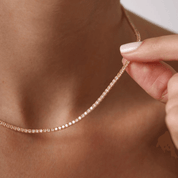 2 mm moissanite tennis necklace held at the neckline.
