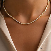 3 mm wide moissanite bezel tennis necklace worn at the neckline.