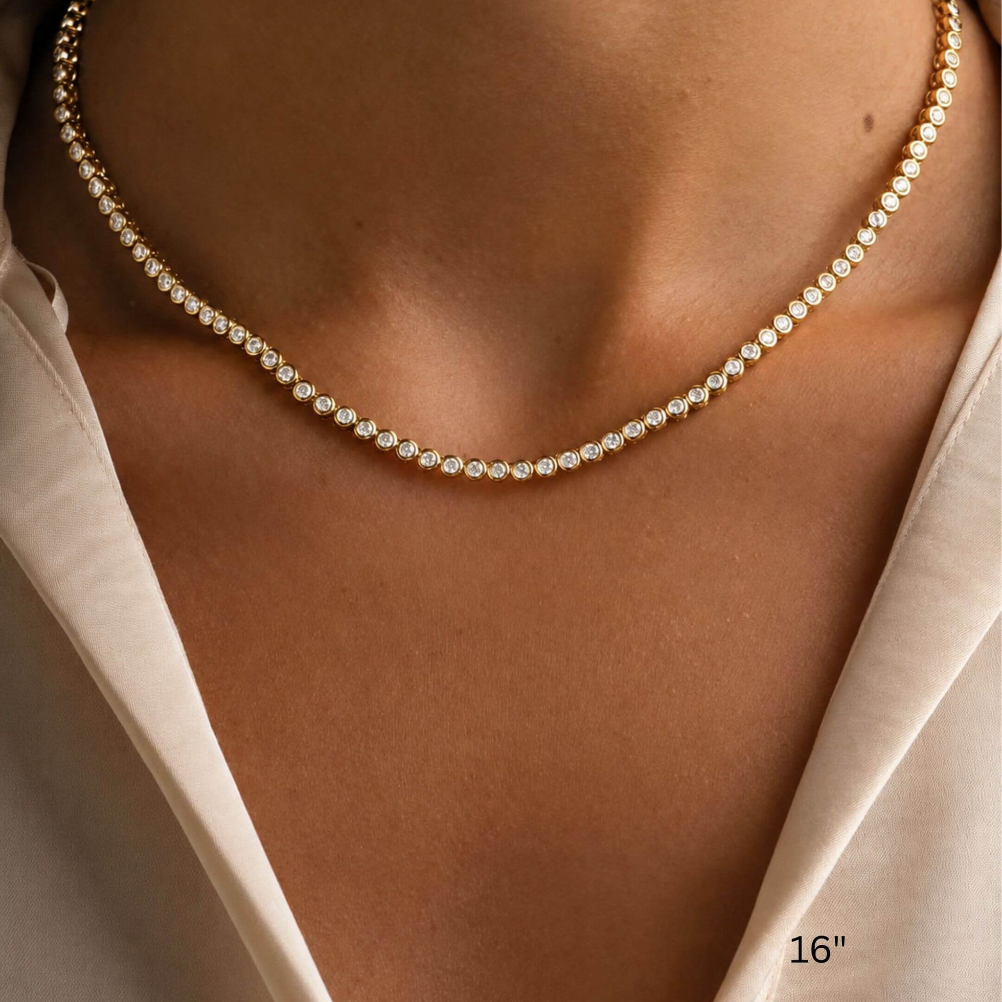 3 mm wide moissanite bezel tennis necklace worn at the neckline.