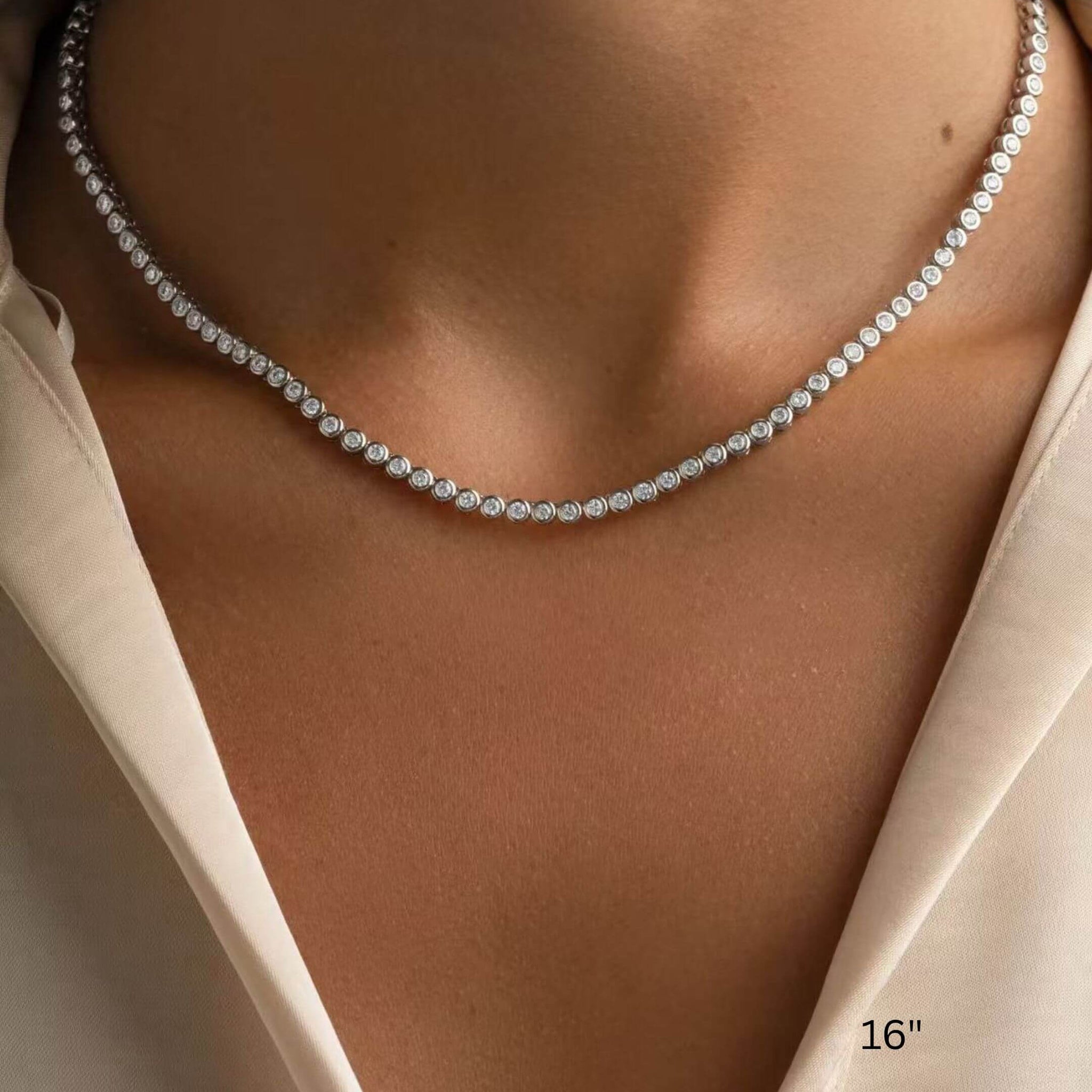 3 mm wide moissanite bezel tennis necklace worn at the neckline.