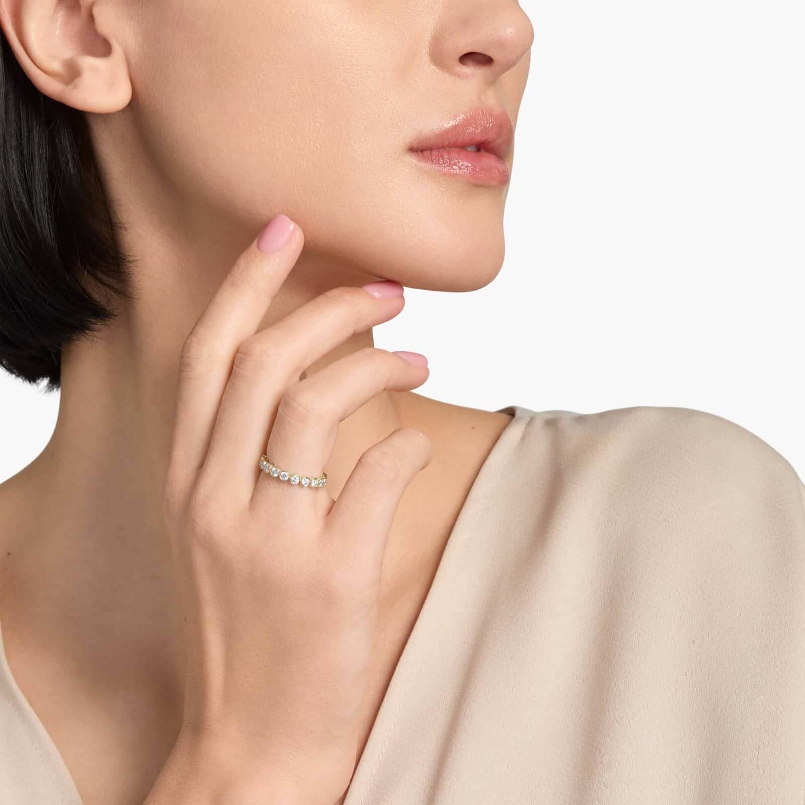 3 mm wide round-cut moissanite bezel eternity ring worn on a finger.