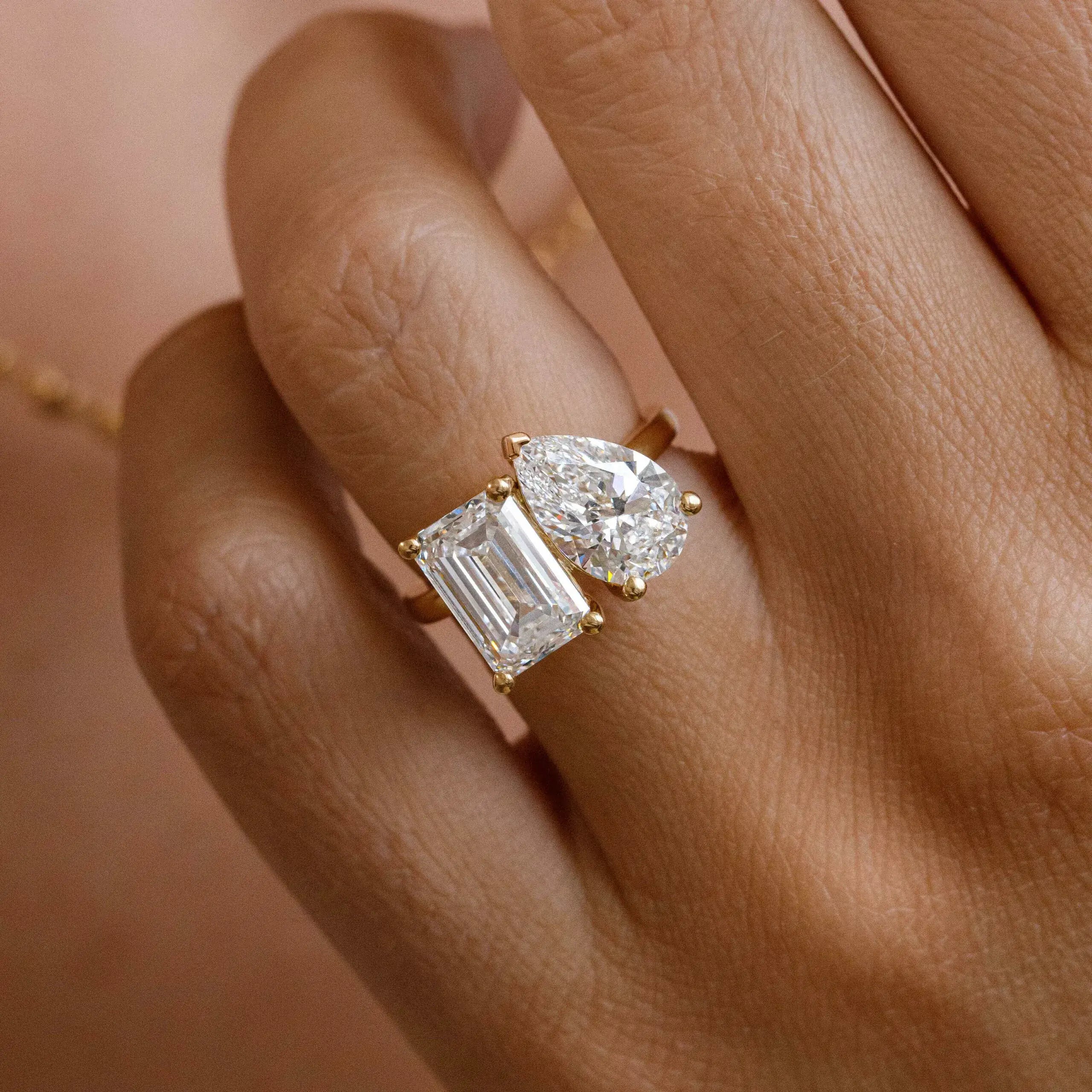 4 ct pear-cut and emerald-cut moissanite toi et moi ring worn on a finger.