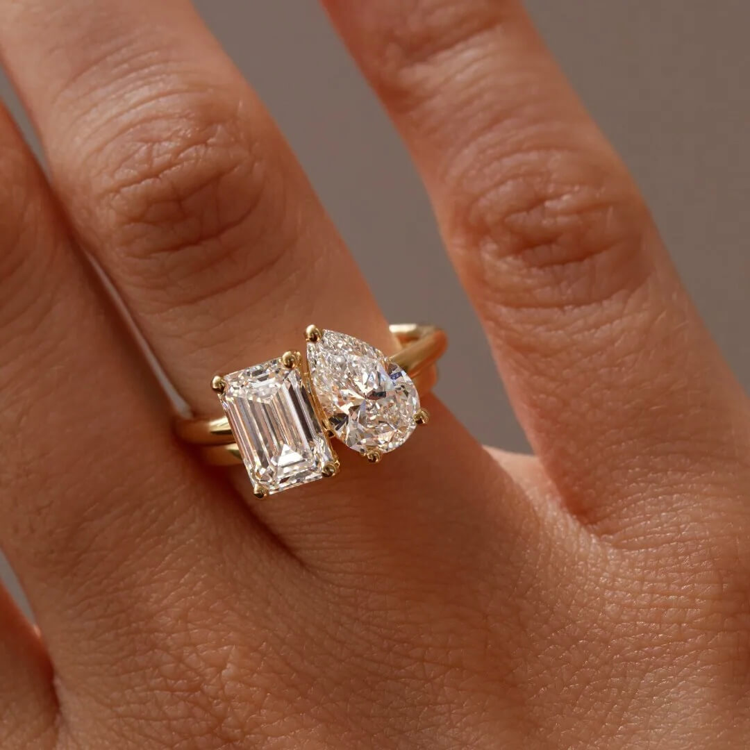 4 ct pear-cut and emerald-cut moissanite toi et moi ring worn on a finger.