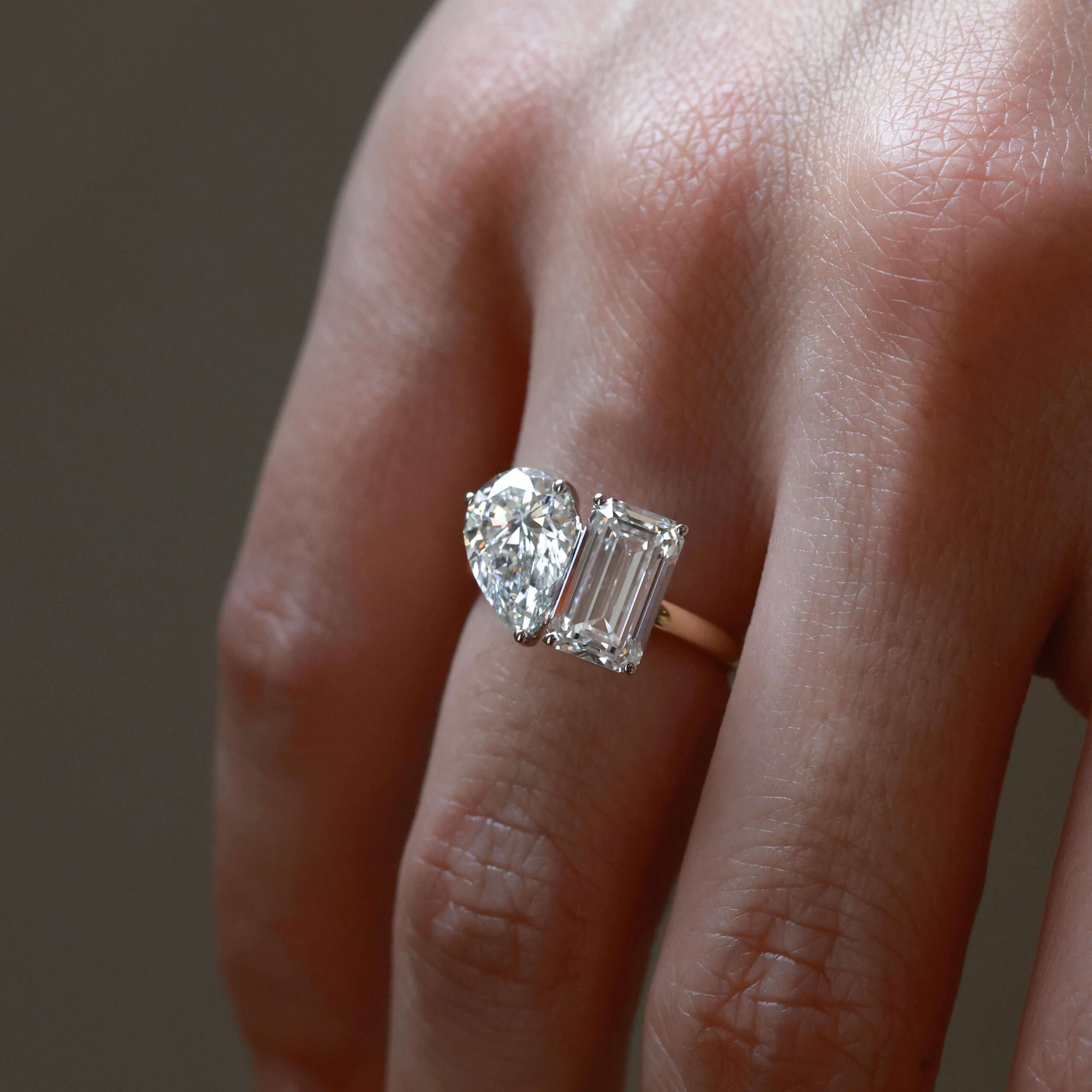 4 ct pear-cut and emerald-cut moissanite toi et moi ring worn on a finger.