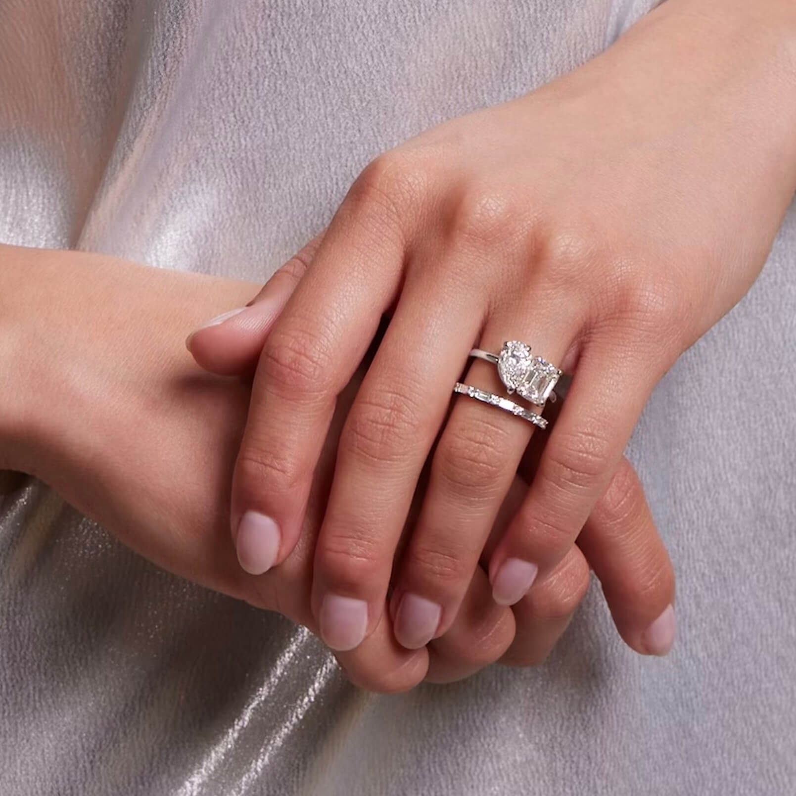 4 ct pear-cut and emerald-cut moissanite toi et moi ring worn on a finger.