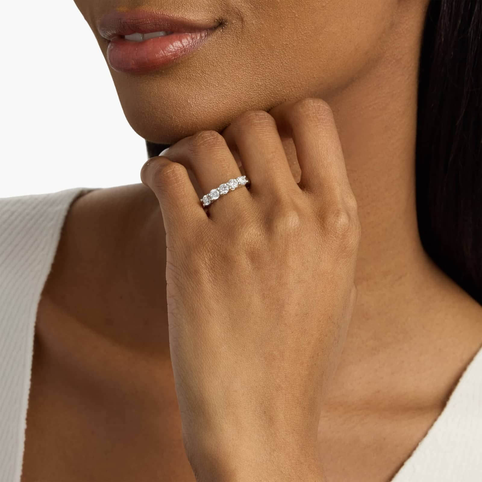 4 mm moissanite half eternity ring worn on a finger.