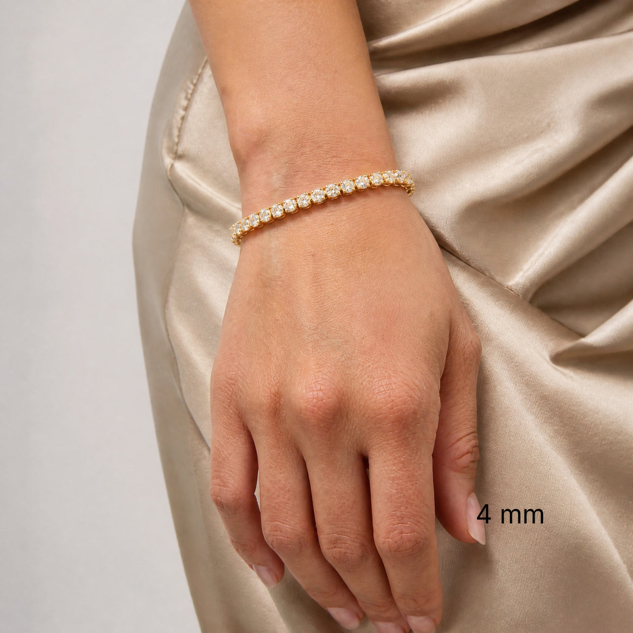 4 mm moissanite tennis bracelet in yellow gold vermeil worn against satin outfit, black 4 mm size label.