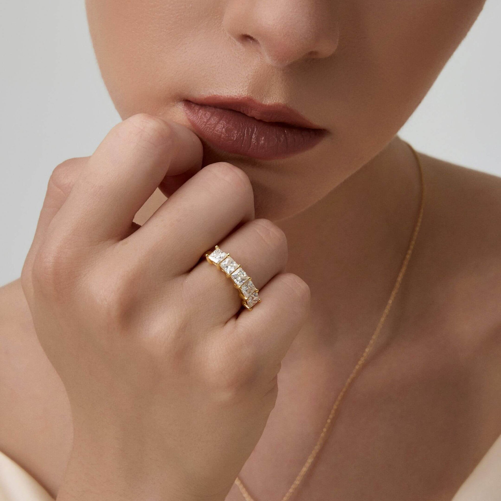 4 mm princess-cut moissanite half eternity ring worn on a finger.
