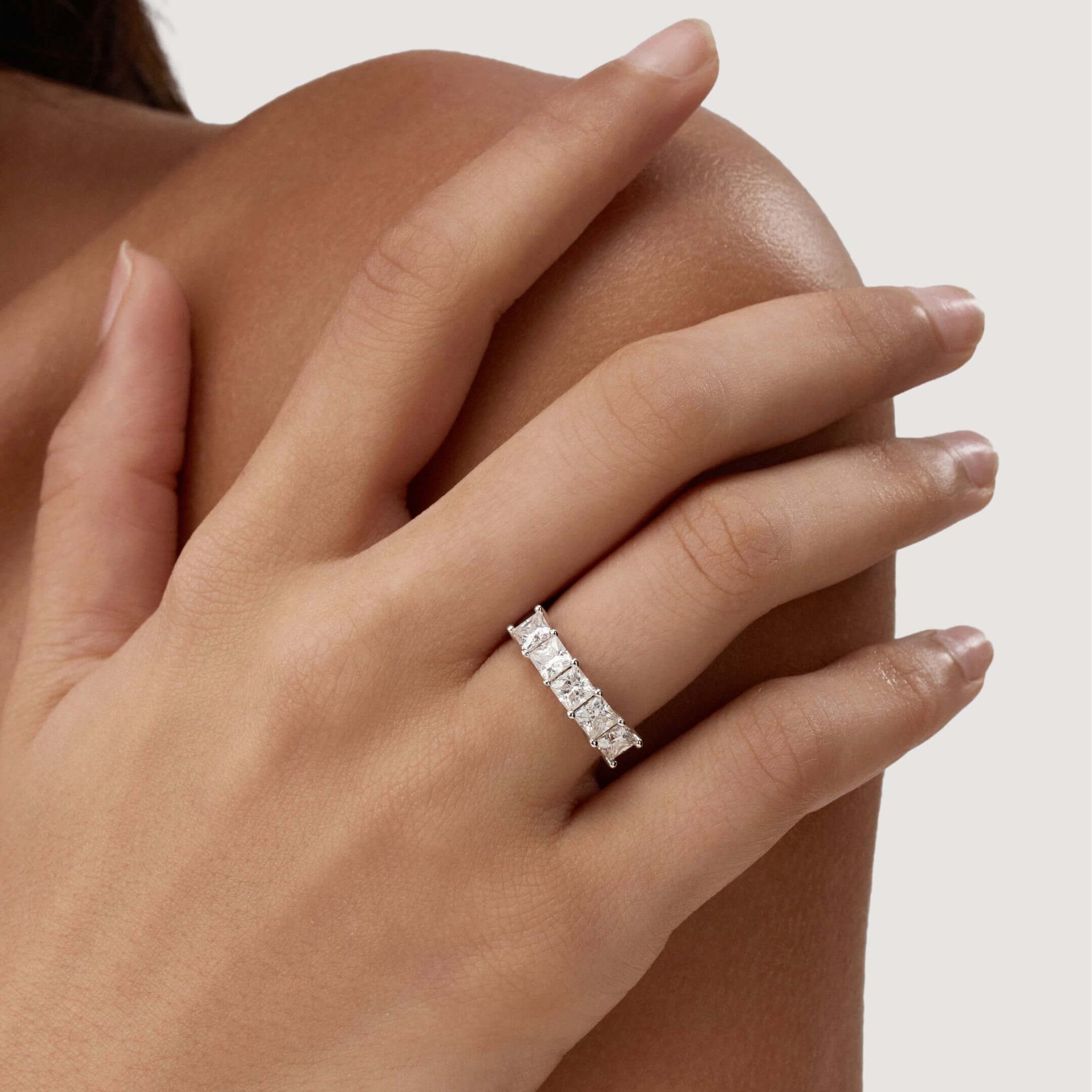 4 mm princess-cut moissanite half eternity ring worn on a finger.