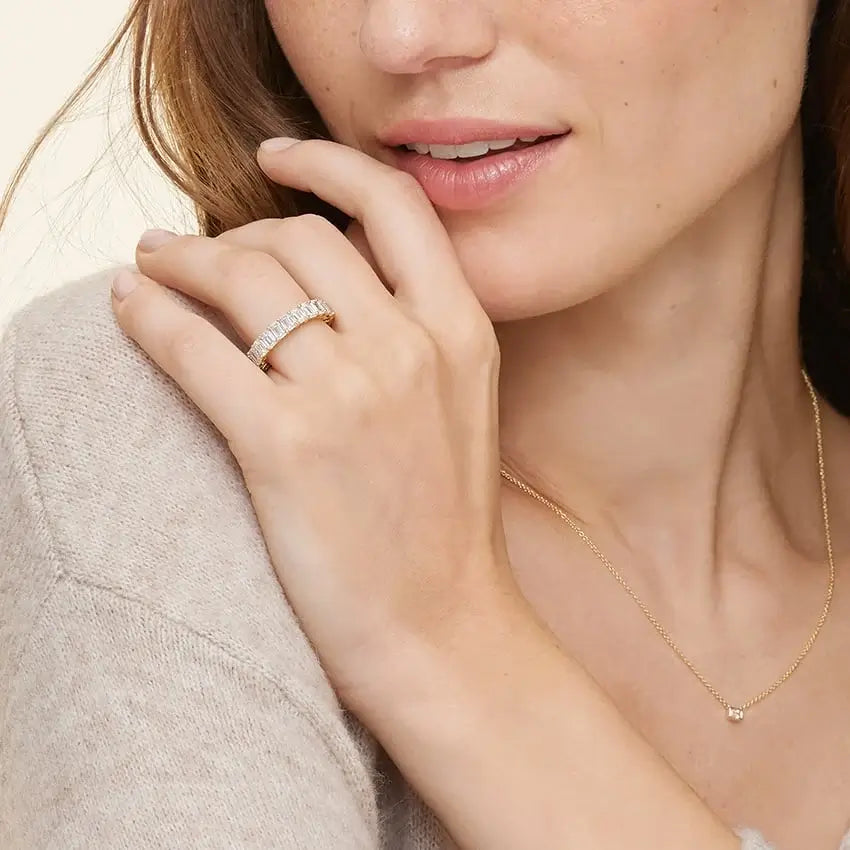 6 ct emerald-cut moissanite eternity ring worn on a finger.