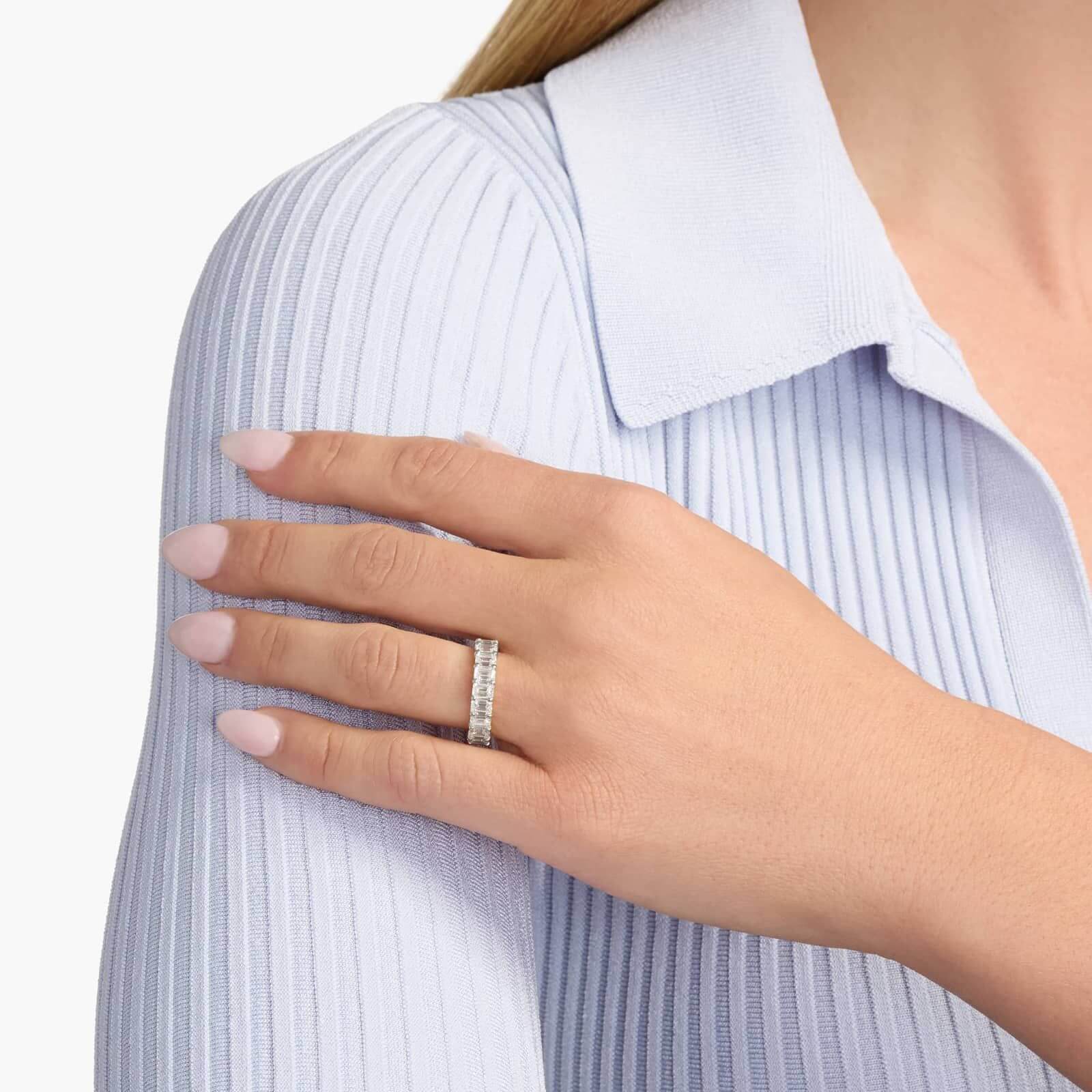 6 ct emerald-cut moissanite eternity ring worn on a finger.