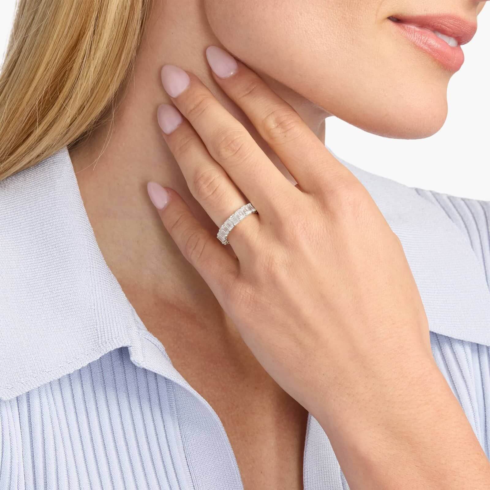 6 ct emerald-cut moissanite eternity ring worn on a finger.