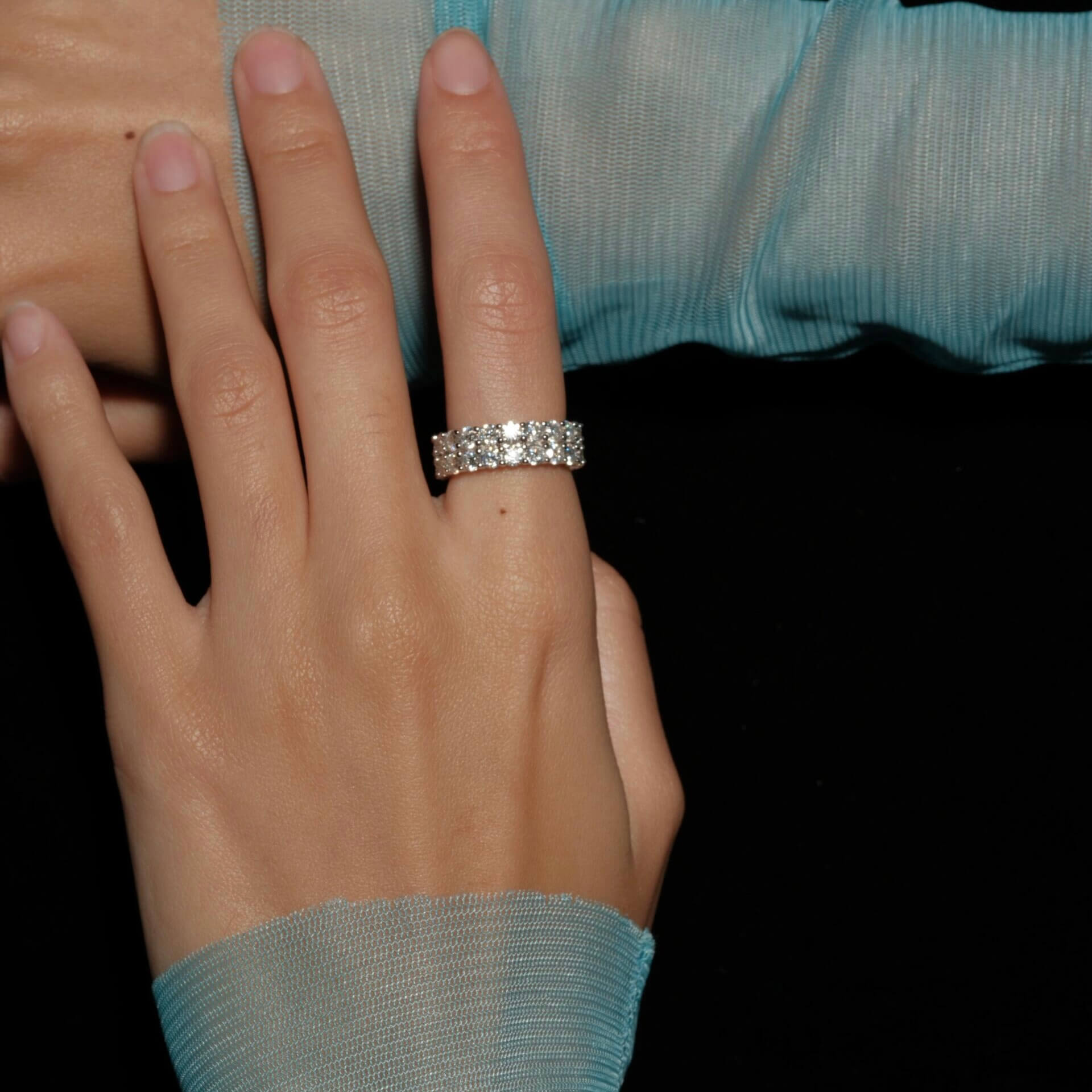 6 mm wide moissanite double-row eternity ring worn on a finger.