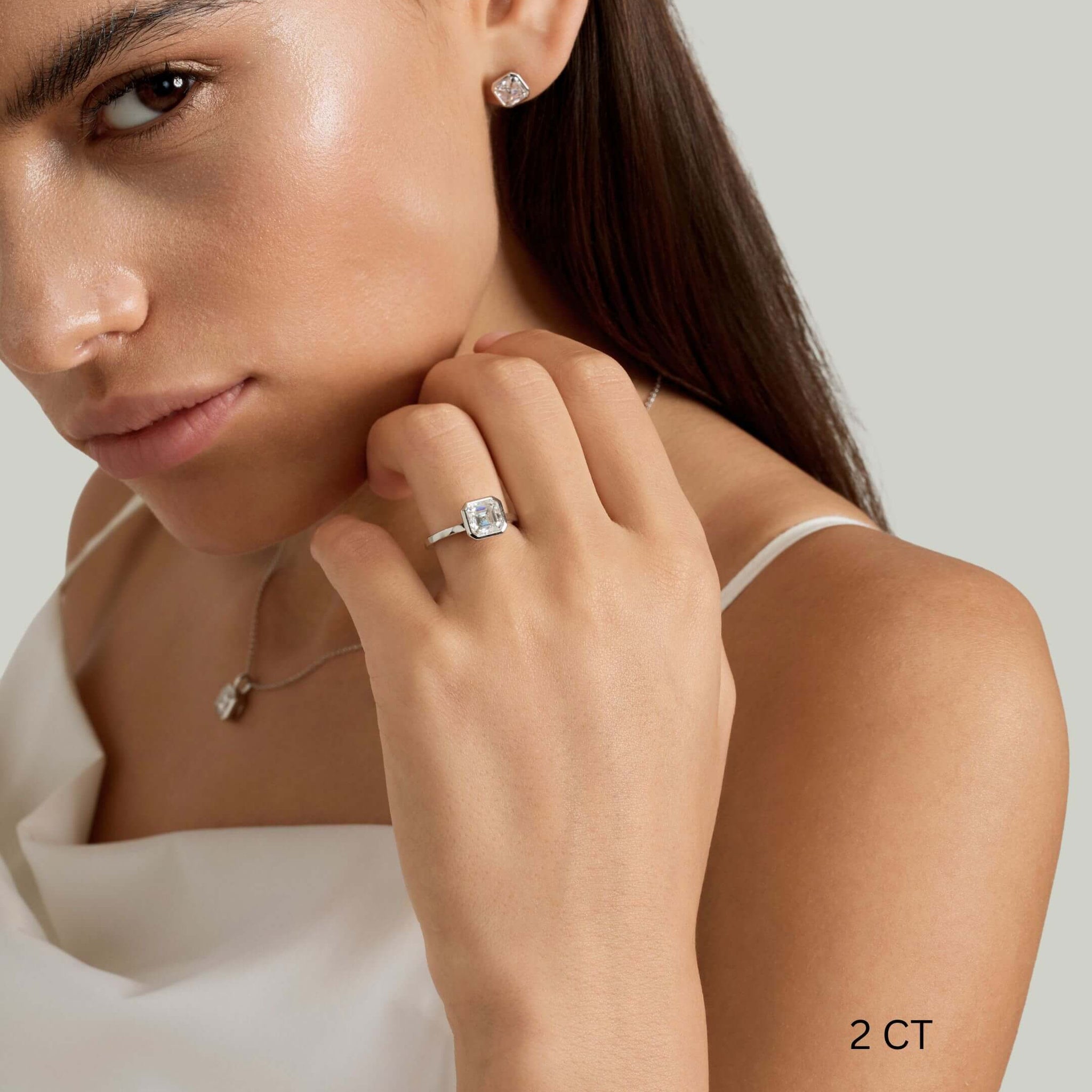 Asscher-cut moissanite bezel solitaire ring worn on a finger with a 2 ct size label.