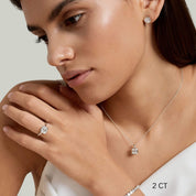 Asscher-cut moissanite bezel stud earrings worn on the ear with a 2 ct size label.