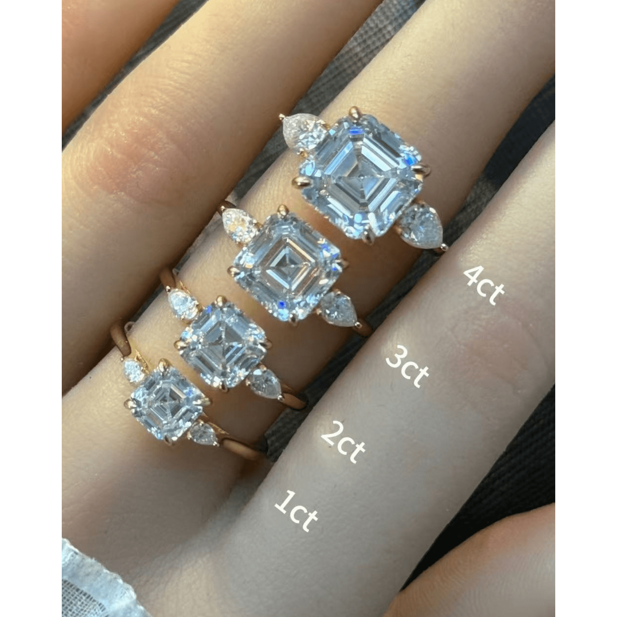 Asscher-cut moissanite three-stone ring rings arranged across fingers for a carat-size comparison.