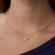 Baguette-cut and round-cut moissanite pendant necklace worn at the neckline.