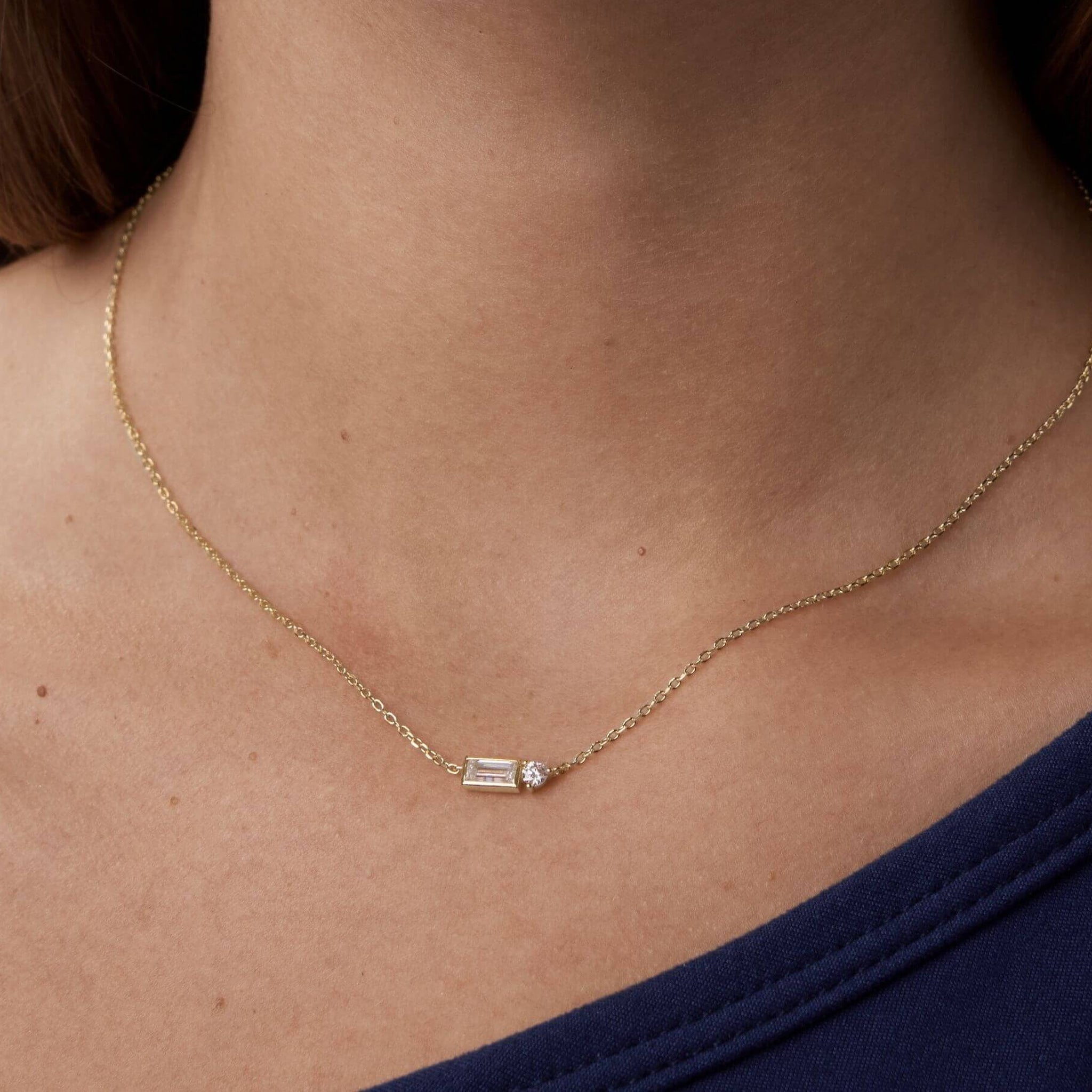 Baguette-cut and round-cut moissanite pendant necklace worn at the neckline.