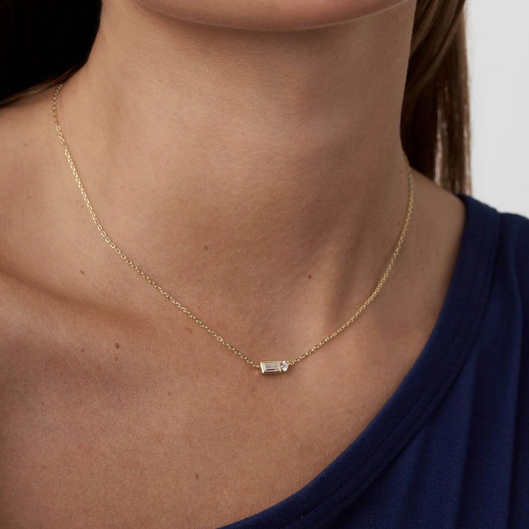 Baguette-cut and round-cut moissanite pendant necklace worn at the neckline.