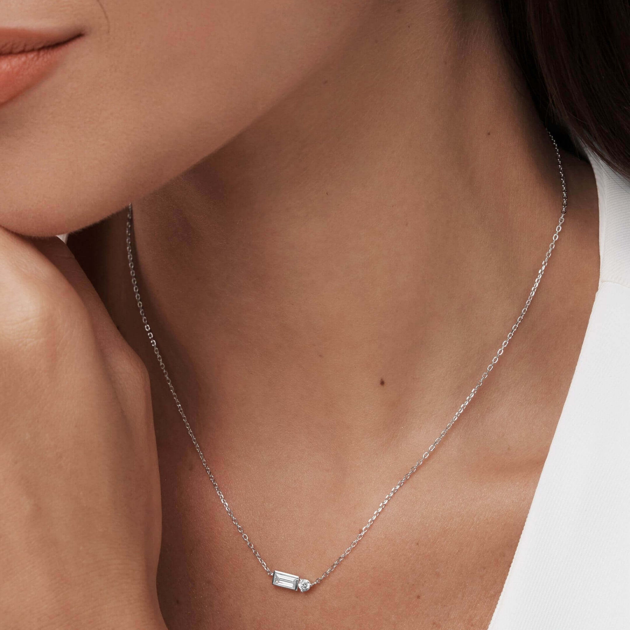 Baguette-cut and round-cut moissanite pendant necklace worn at the neckline.