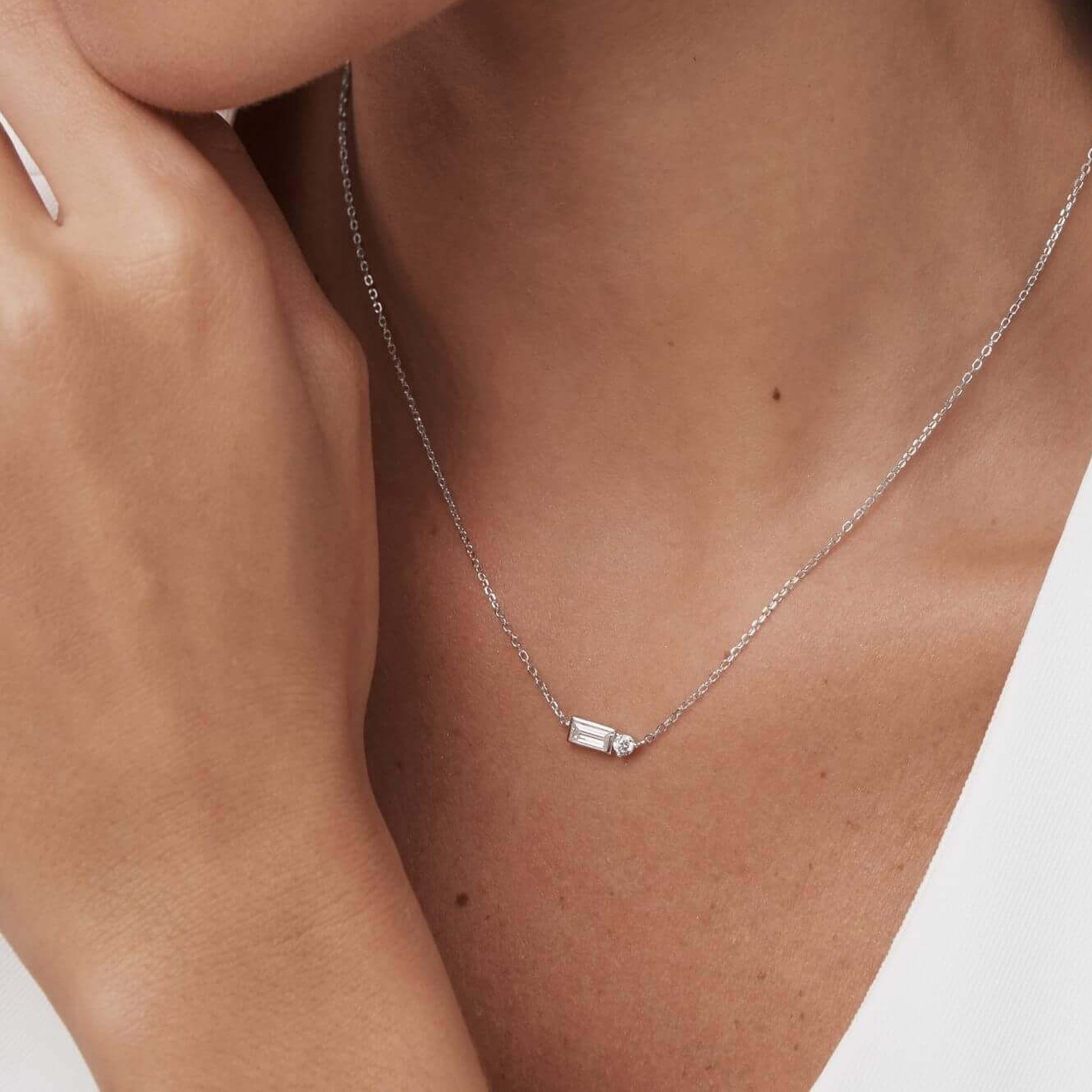 Baguette-cut and round-cut moissanite pendant necklace worn at the neckline.