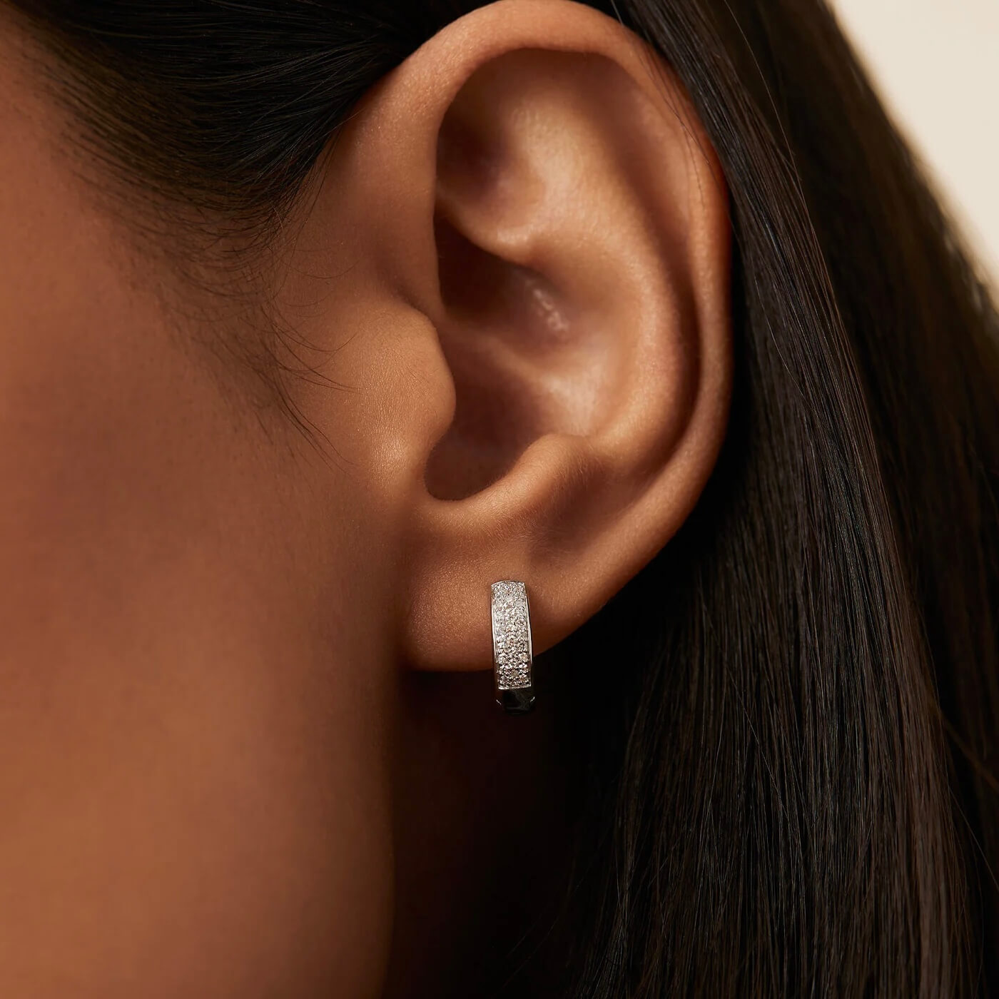 Bold pavé moissanite huggie hoop earrings worn on the ear.