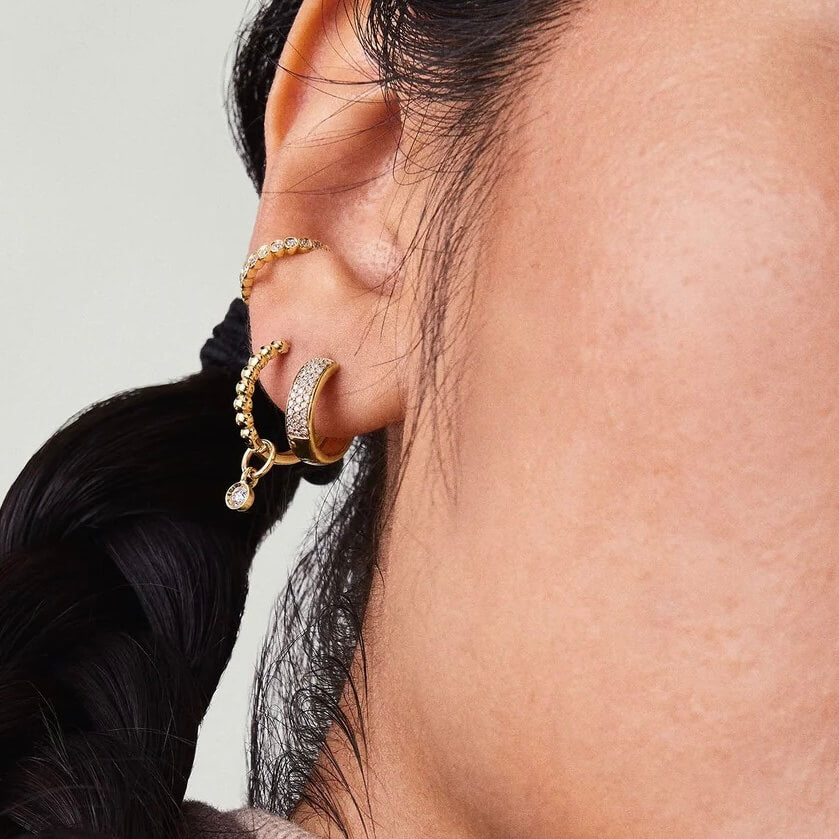 Bold pavé moissanite huggie hoop earrings worn on the ear.