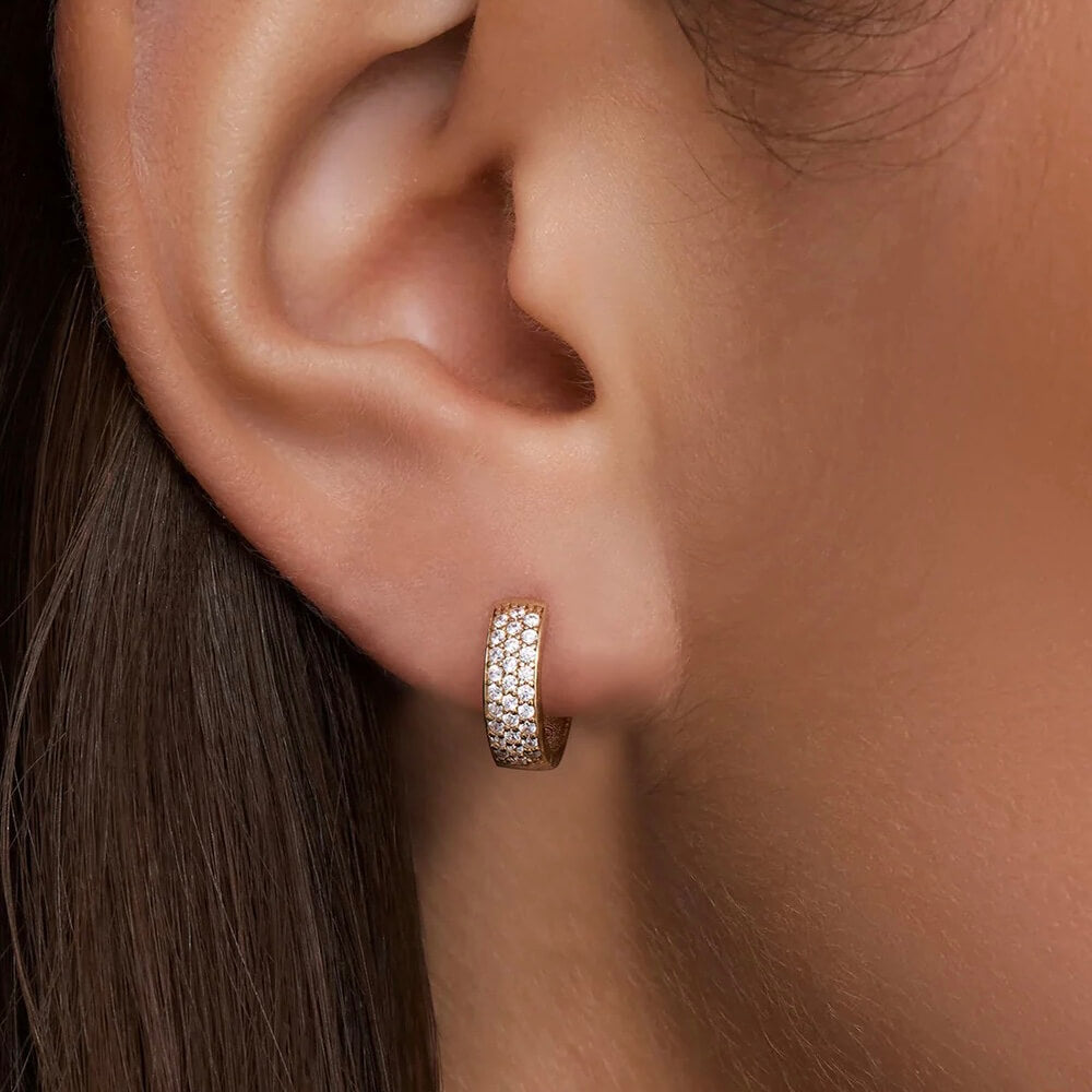 Bold pavé moissanite huggie hoop earrings worn on the ear.