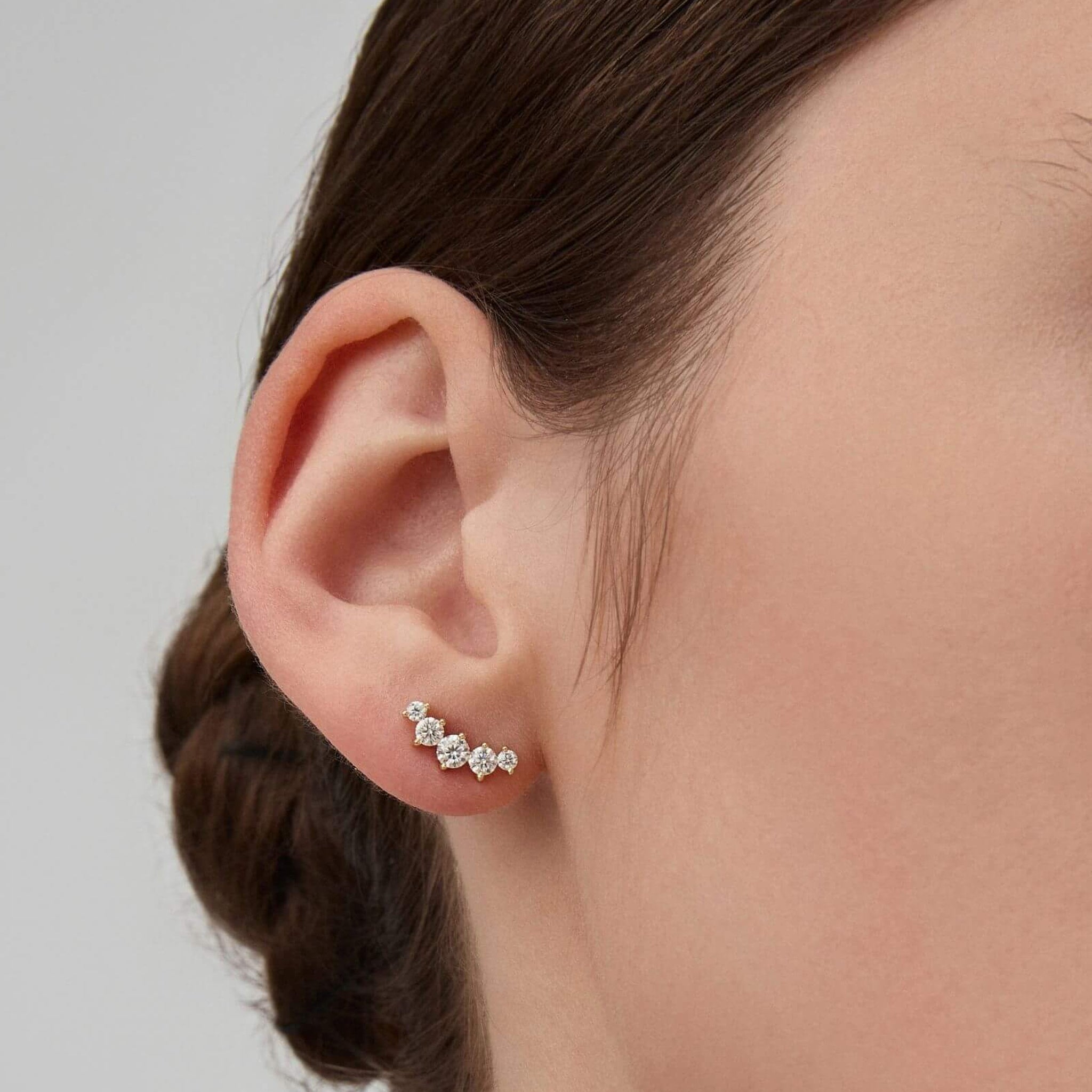 Curved moissanite stud earrings worn on the ear.