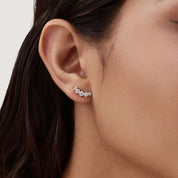 Curved moissanite stud earrings worn on the ear.