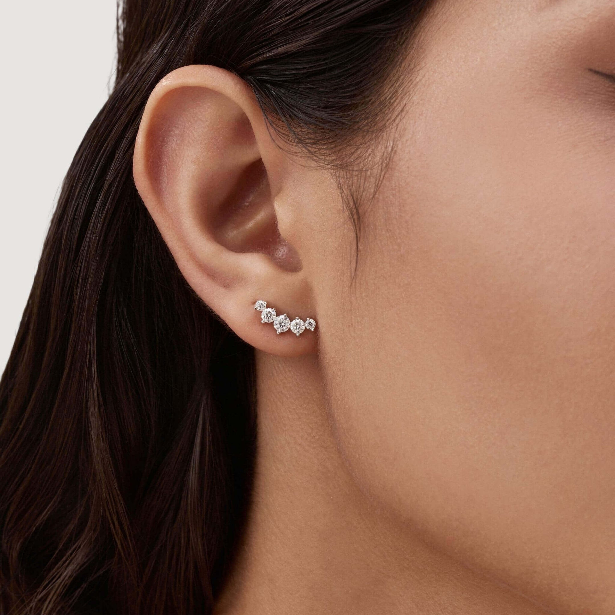Curved moissanite stud earrings worn on the ear.