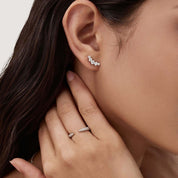 Curved moissanite stud earrings worn on the ear.