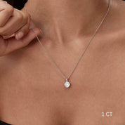 Cushion-cut moissanite bezel pendant necklace worn at the neckline.