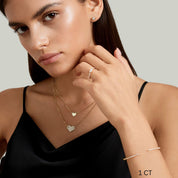 Cushion-cut moissanite bezel stud earrings worn on the ear with a 1 ct size label.