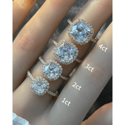 Cushion-cut moissanite halo ring with pavé band rings arranged across fingers for a carat-size comparison.