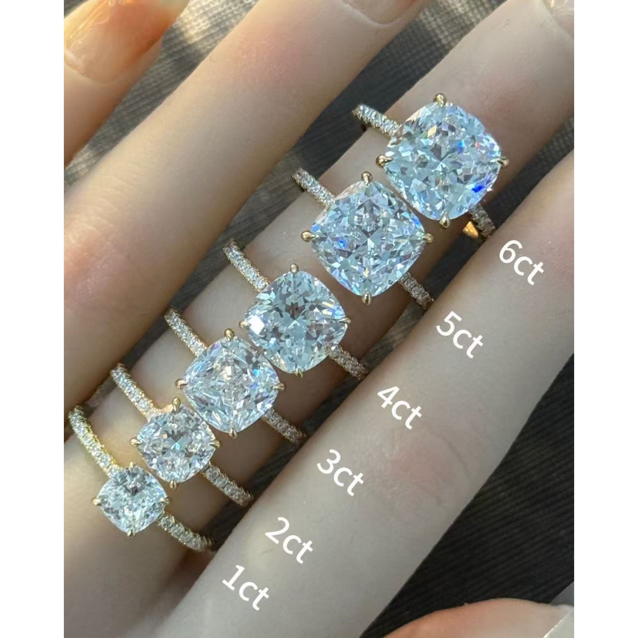Cushion-cut moissanite hidden halo ring with pavé band rings arranged across fingers for a carat-size comparison.