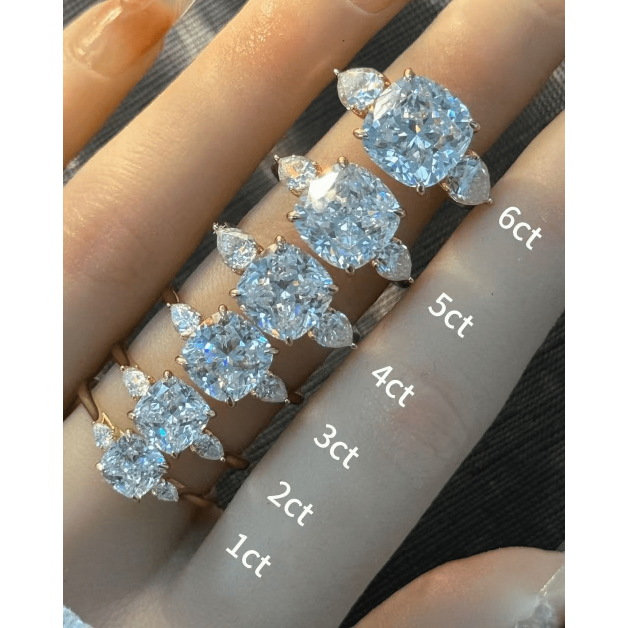 Cushion-cut moissanite three-stone ring rings arranged across fingers for a carat-size comparison.