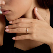 East-west radiant-cut moissanite solitaire ring with pavé band worn on a finger.