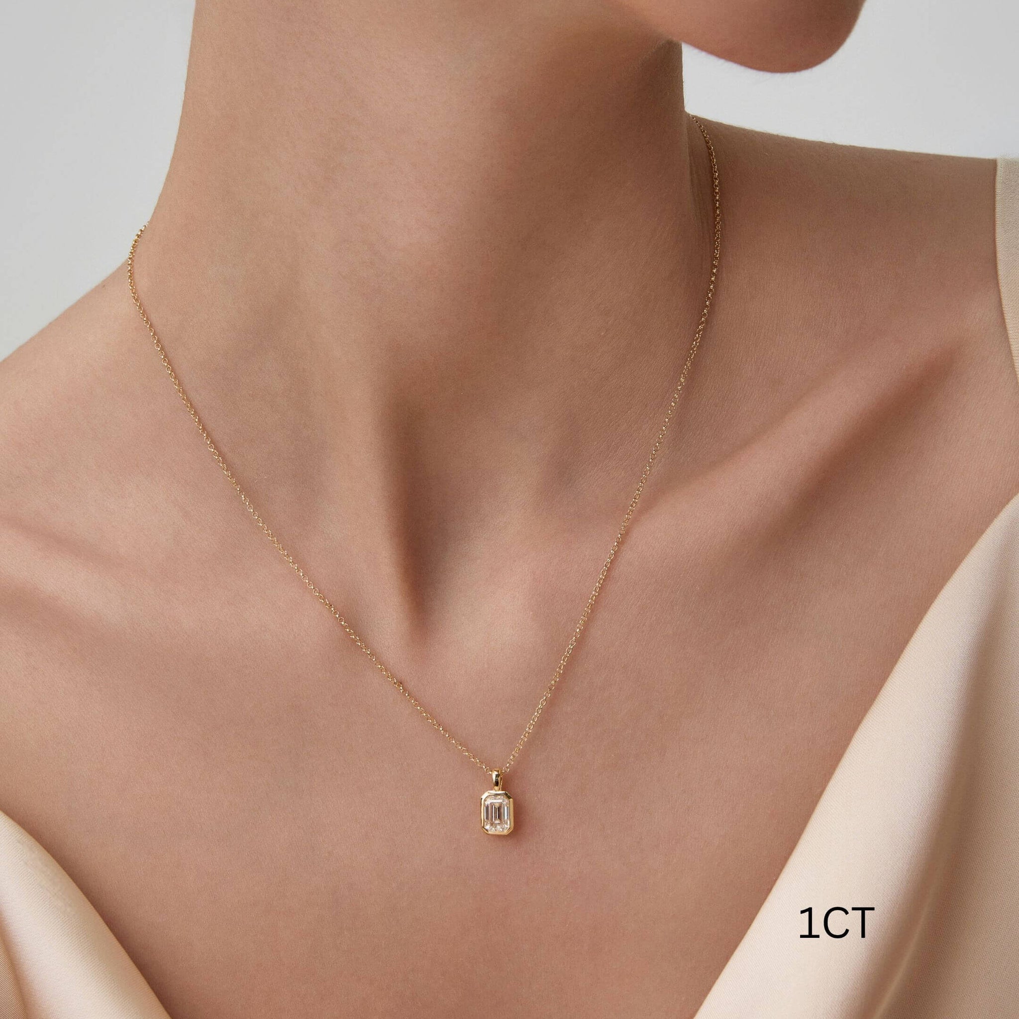 Emerald-cut moissanite bezel pendant necklace worn at the neckline.
