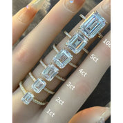Emerald-cut moissanite hidden halo ring with pavé band rings arranged across fingers for a carat-size comparison.
