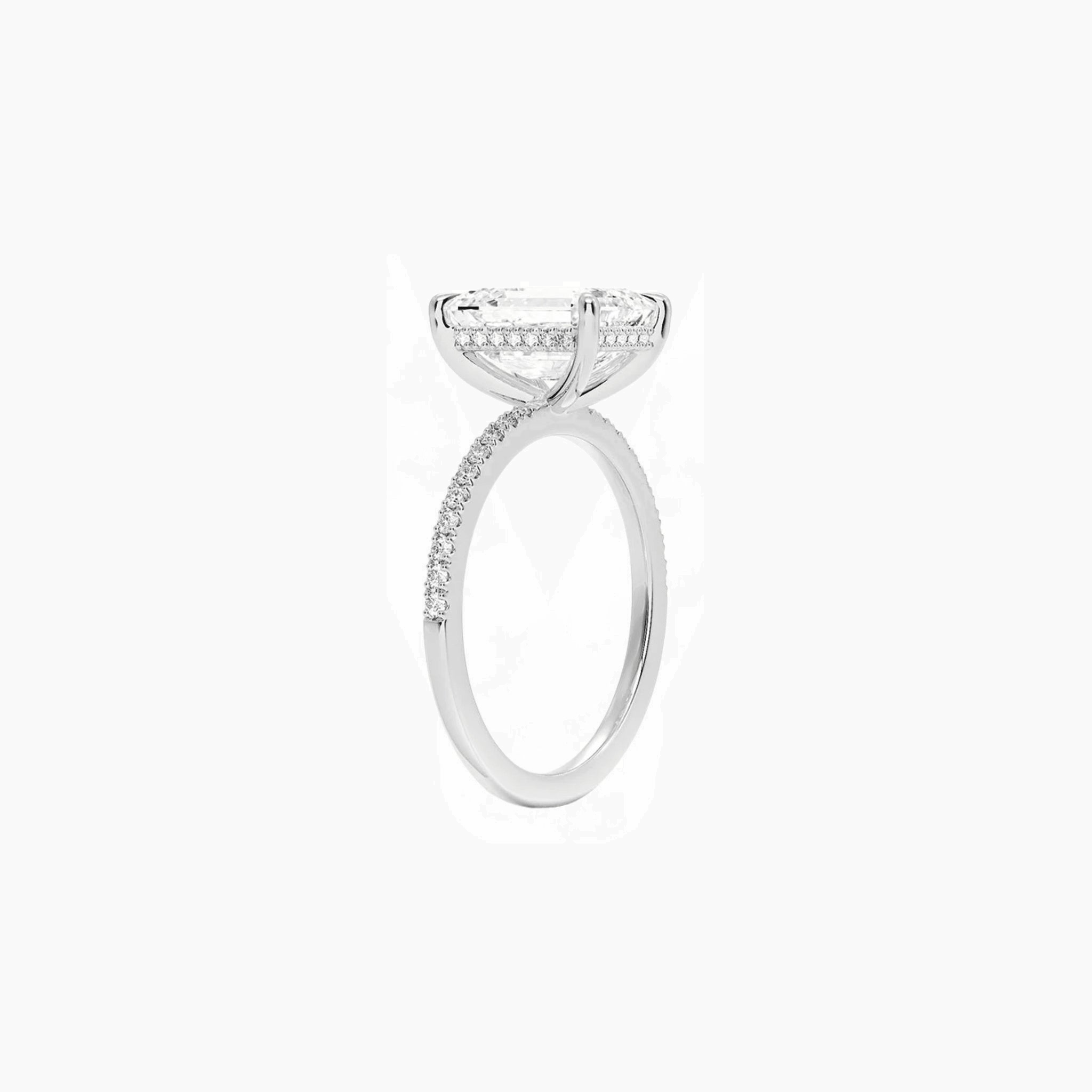 Emerald-cut moissanite hidden halo ring with pavé band in white gold vermeil, side view.